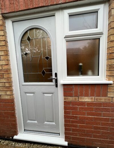 Grey composite door with decorative glass in a white frame - Glazerite uPVC