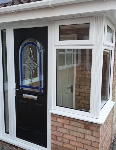 Black composite door with decorative glass in a white frame - Glazerite uPVC