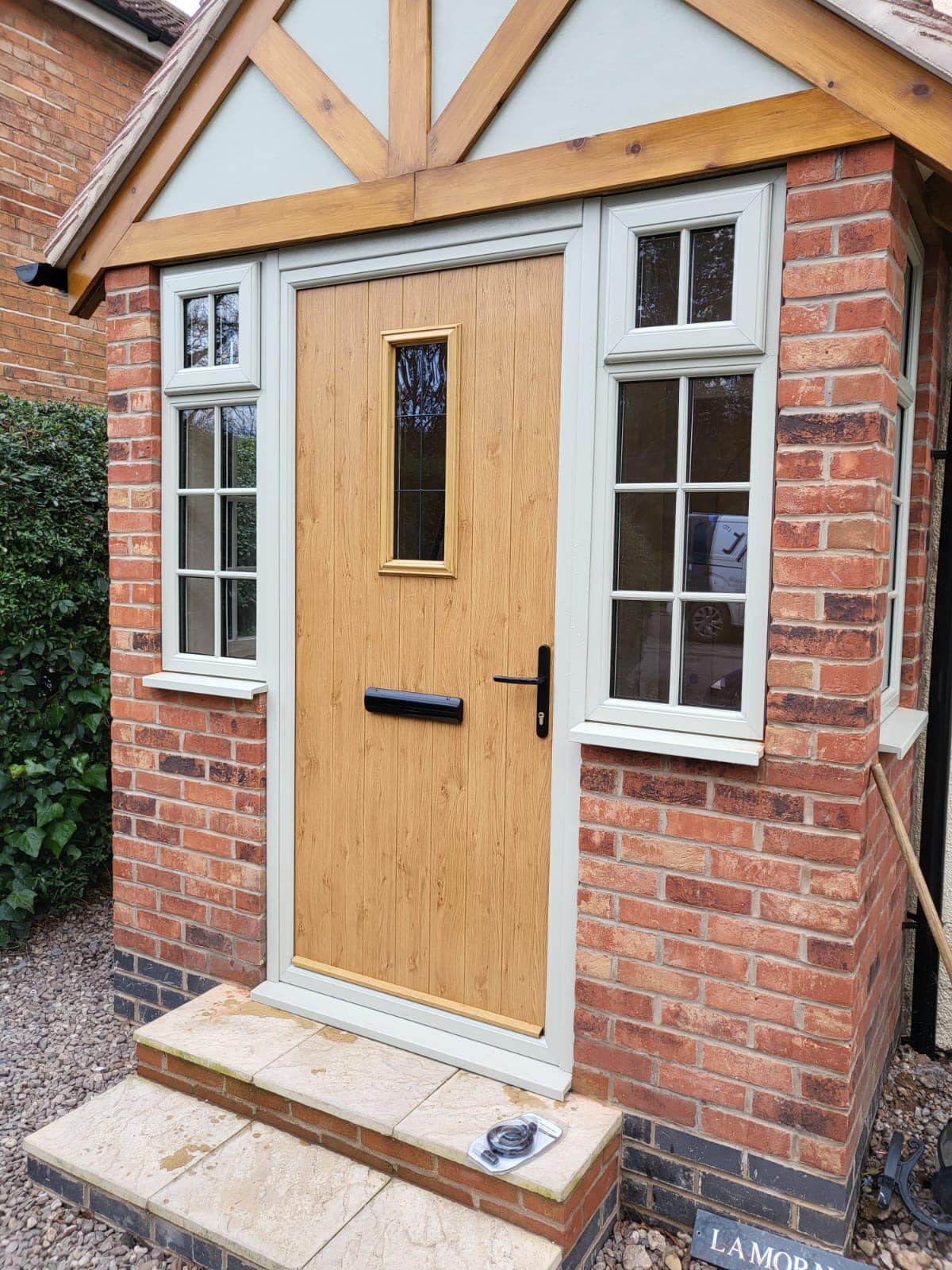 com_ Irish oak composite residential door with black handle and letterplate on agate grey frame - Glazerite uPVC