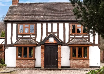 Older tudor style farm house property with dark brown wooden entrance door and dark wood effect flush casement upvc windows - Glazerite uPVC