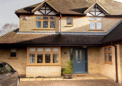 Property with grey composite entrance door and irish oak flush casement windows - Glazerite uPVC