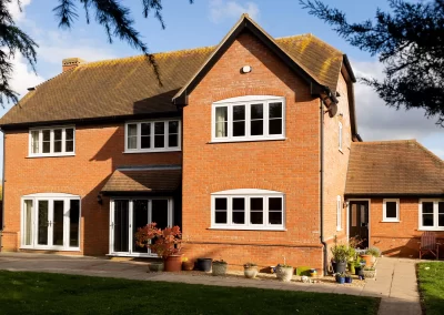 Back of house with white upvc flush casement windows, upvc french patio doors, and white aluminium bifold patio doors - Glazerite uPVC